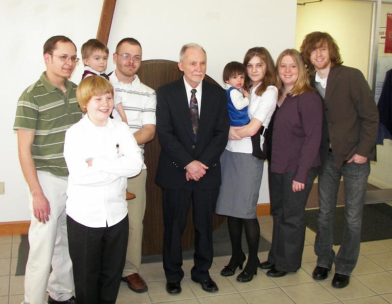 jimandgrandchildren030708.jpg - Jim and 8 Grandchildren present at Sandy's Memorial Service, March 7, 2008.  L to R  Kyle Thomas;  in front = Dylan Clark;  Adam Wenze being held by Tyler Thomas;  Jim Clark;  Ana Maria Negrete being held by Sarah Chlarson;  Rachel Pavilanis;  Taylor Clark.  Sarah Chlarson sang the song, "Will There Be Any Stars In My Crown" and Taylor Clark sang the song, "Sunshine On My Shoulder", during the Memorial Service.